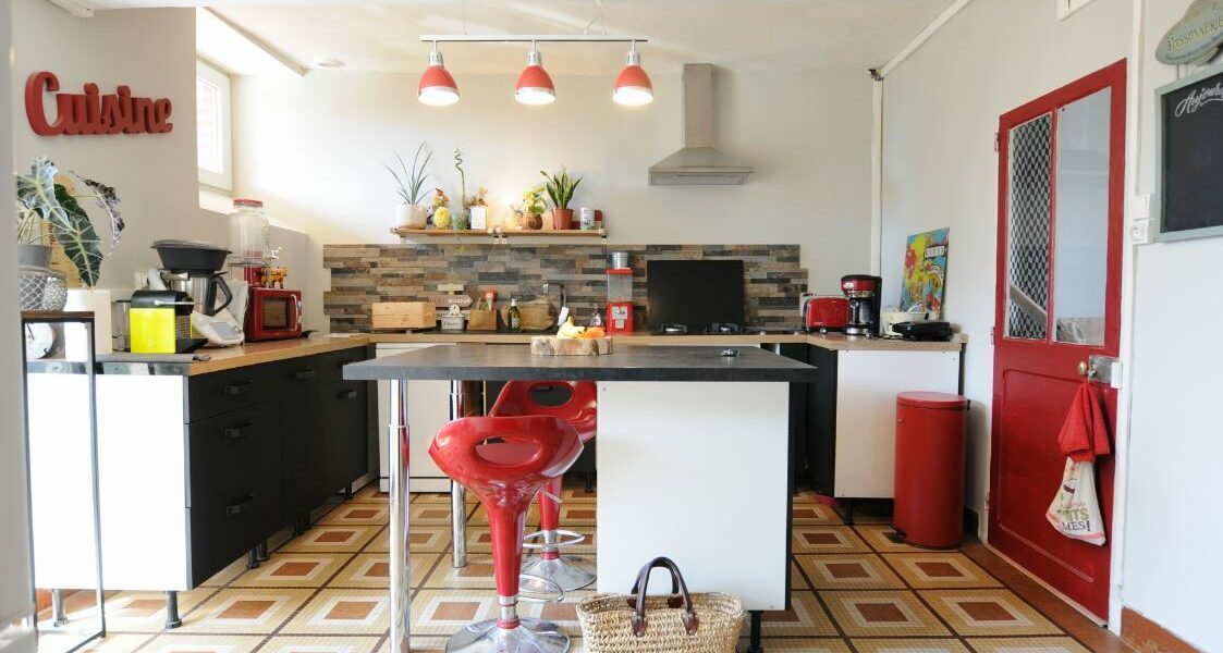 vue cuisine réaménagée aux teintes rouges bois et noir
